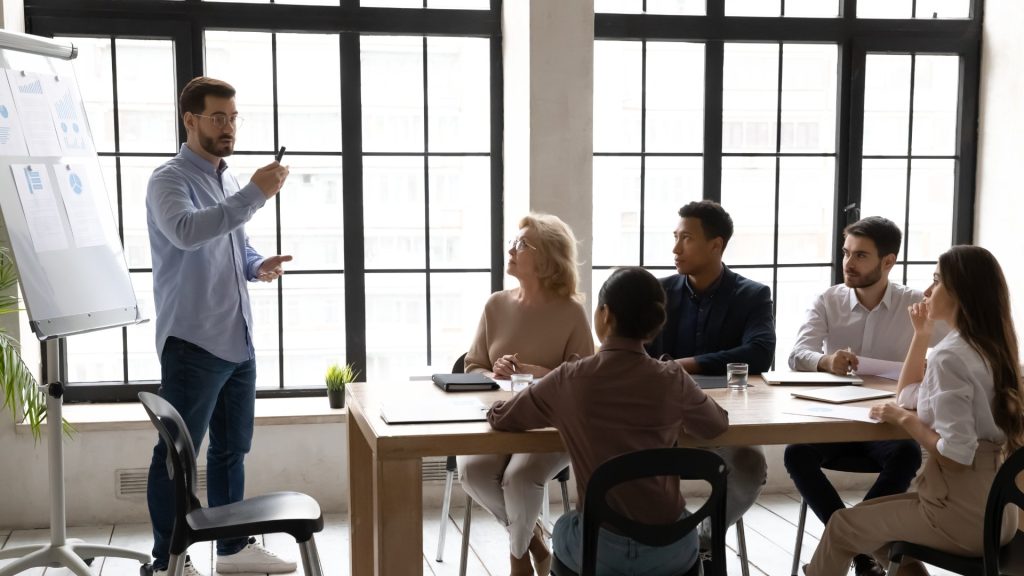 Hombre explica algo de una pizarra en una reunión